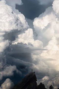 человек на скале, над ним громадные суровые облака